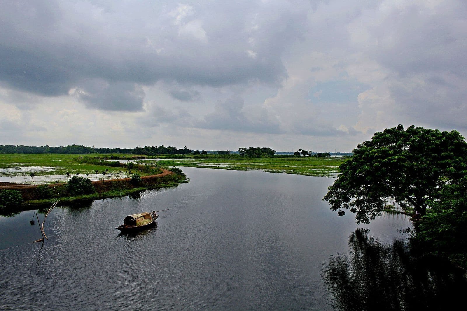 মেঘলা আকাশের নিচে কালীগঞ্জের বেলাই বিলে নৌকা